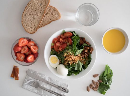 Top view of a nutritious breakfast with salad, eggs, bread, and juice, perfect for a healthy start.