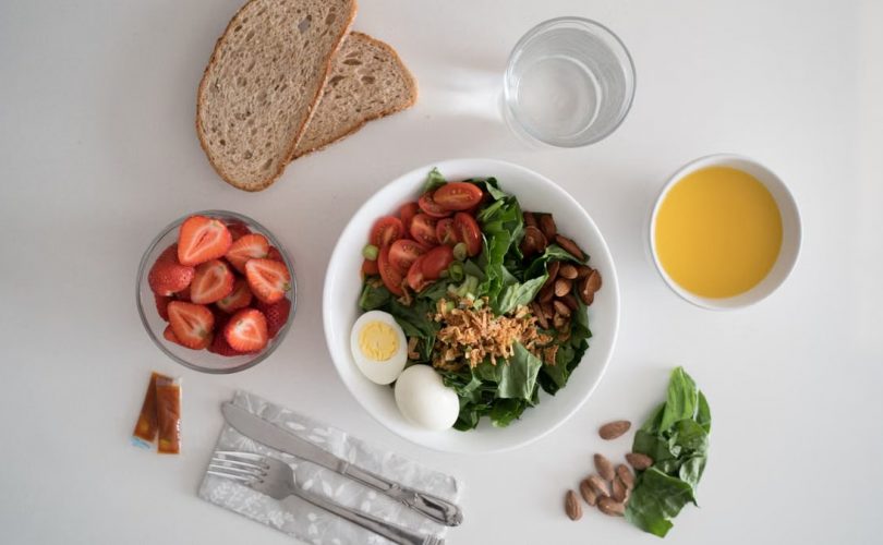 Top view of a nutritious breakfast with salad, eggs, bread, and juice, perfect for a healthy start.