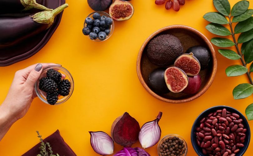 Colorful assortment of fruits and vegetables on a yellow backdrop, highlighting healthy eating.
